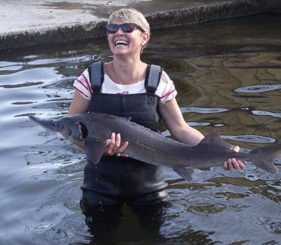 femme portant un esturgeon dans un bassin